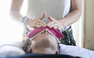 Image of patient beginning their holistic medicine visit with an eye pillow over their eyes.